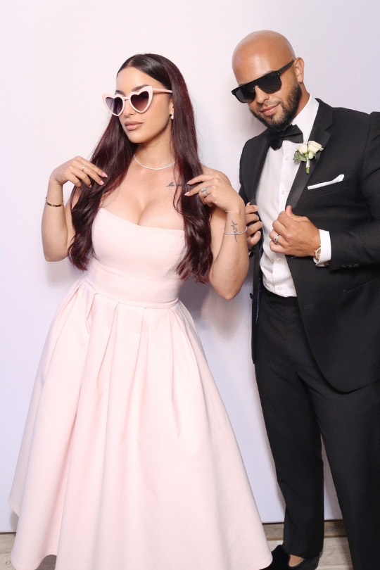 Anthony y Leyla posando con estilo —gafas de corazón y esmoquin— en el fotomatón de su boda en Casa Del Mar, Sitges