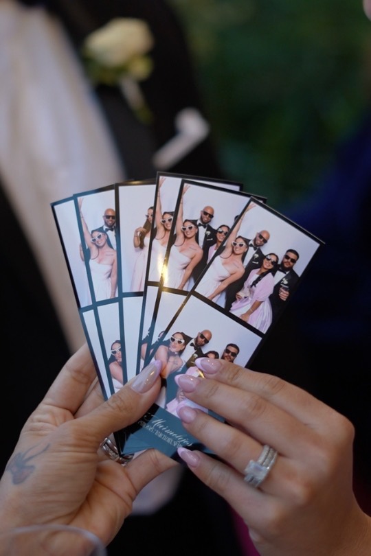 Manos sosteniendo en abanico varias tiras de fotos del fotomatón de la boda