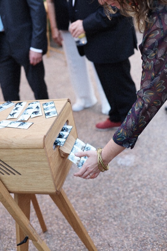 Una invitada recoge su tira de fotos del fotomatón entre los chaqués de la boda — Mas Les Lloses, Sagunto
