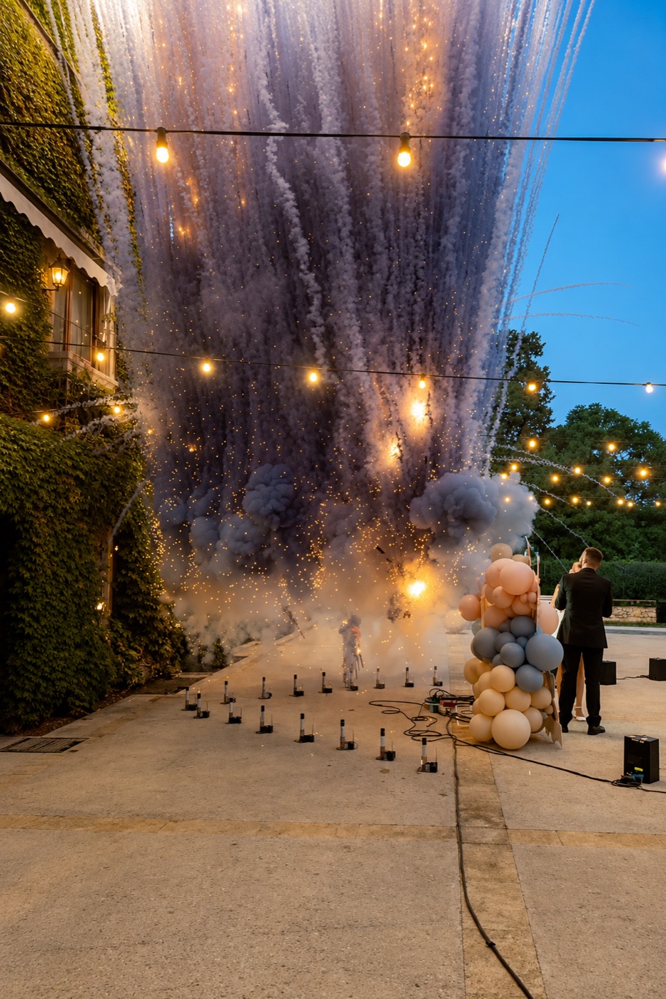 Cascada de humo aéreo sobre la fila de disparos junto al muro — boda en Casa Santonja, Alicante